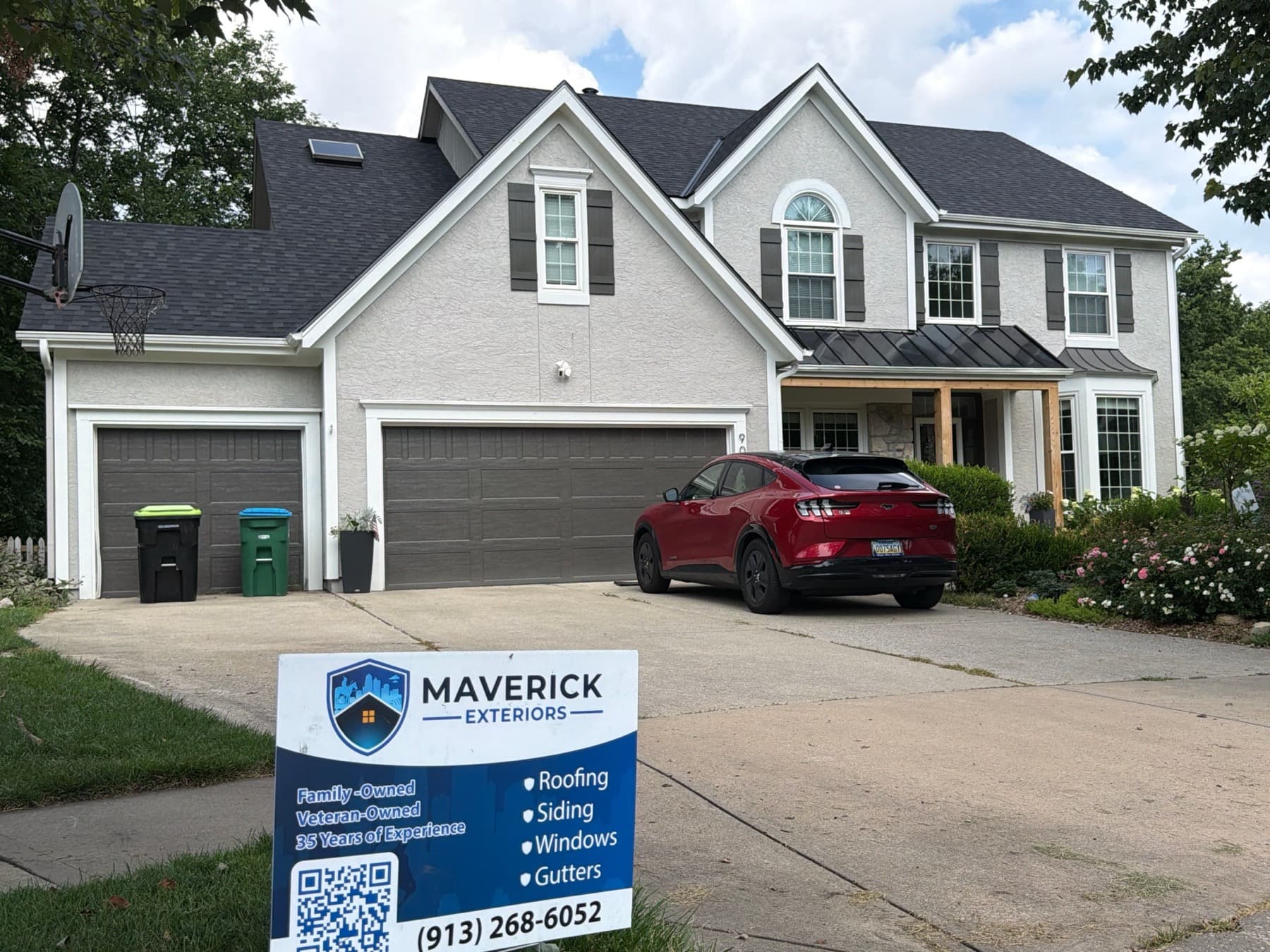 A completed shingle roof on a two-story home with a Maverick Exteriors sign in the front yard